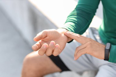 Sportif genç adam antrenmandan sonra nabzını kontrol ediyor, yakın plan.
