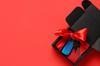 Kırmızı arka planda yeni arabanın anahtarlarının olduğu hediye kutusu