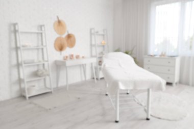Kanepesi, mumları ve beyaz mobilyaları olan bulanık spa salonu manzarası