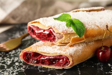 Arka planda siyah tabakta vişneli turta, yakın plan.