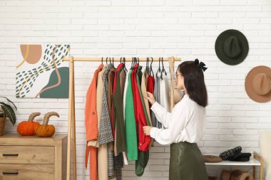 Soyunma odasında şık elbiseleri olan genç bir kadın.