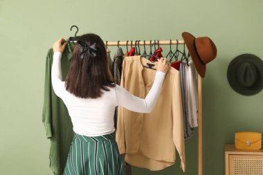 Genç bir kadın soyunma odasında kıyafet seçiyor.