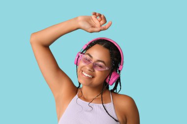 Duygusal Afro-Amerikalı kadın mavi arka planda müzik dinliyor.