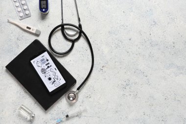Beyaz grunge arka planında cep telefonu ve tıbbi malzemeler. Teletıp kavramı