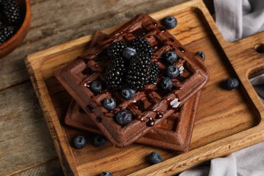 Tahta arka planda taze böğürtlen ve yabanmersinli Belçika waffle 'ı.