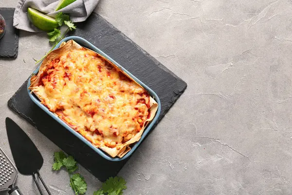 Lezzetli enchilada, baharatlar ve grunge arkaplanda mutfak gereçleri ile pişirme yemeği.