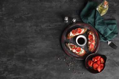 Lezzetli domates bruschetta ile ricotta ve siyah arka planda bir kase sos.