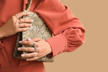 Renkli arka planda güzel manikürlü ve şık çantalı kadın, yakın plan.