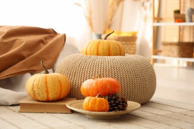 Balkabaklı puf ve yatak odasındaki halıda kitap.