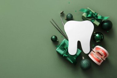 Kağıt dişli kompozisyon, dişçi aletleri, Noel hediyeleri ve yeşil arka planda süslemeler