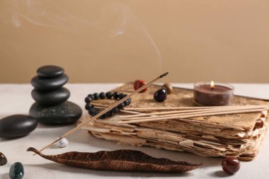 Renk duvarına karşı aromatik tütsü çubukları, eski kitap ve spa taşlarıyla kompozisyon