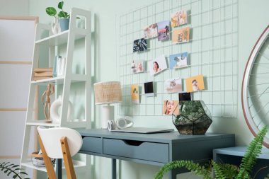 Yeşil duvarda dizüstü bilgisayarı ve ruh hali panosu olan bir çalışma odası.