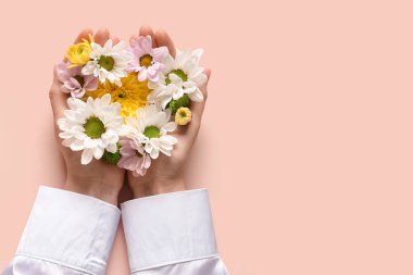Bej arka planda taze çiçekleri olan kadın elleri. Bakım kavramı