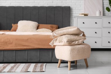 Yastıklı yumuşak rahat yatak, çekmeceler ve yatak odasının iç tarafında yastıklı puf.