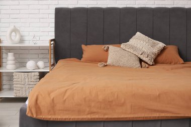 Yatak odasında yastıkları ve raf ünitesi olan yumuşak rahat bir yatak.