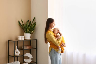 Genç bir anne ve bebeği evde askı içinde.