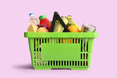 Farklı taze ürünlerle dolu yeşil alışveriş sepeti ve leylak arkaplanda ketçap