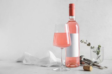 Cam, pembe şarap, kumaş ve tirbuşon beyaz arka planda.