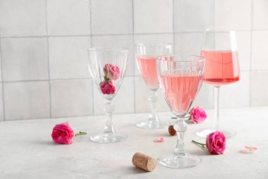 Beyaz fayans zeminine karşı masasında güller ve mantarlarla pembe şarap kadehleri