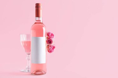 Bir şişe pembe şarap ve pembe arka planda güller.