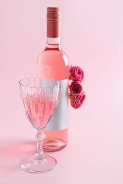 Bir şişe pembe şarap ve pembe arka planda güller.