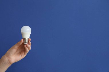 Koyu mavi arka planda beyaz ampullü kadın eli