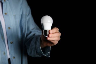 Siyah arka planda ampulü olan bir kadın. Yakın çekim.