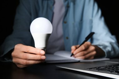 Ampullü kadın siyah arka plan üzerine notlar yazıyor. Yakın çekim.