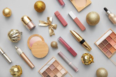Gri arka planda farklı makyaj ürünleri olan güzel Noel süsleri.