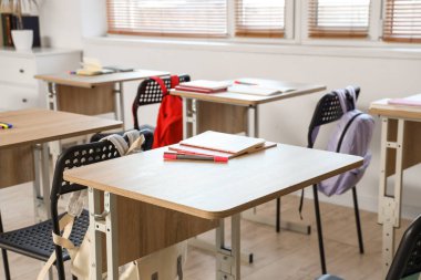 Boş sınıflarda not defterleri ve kalemlerle okul masası, yakın çekim.