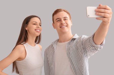 Cep telefonlu genç bir çift arka planda selfie çekiyor.