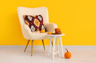 Koltuk ve bir fincan lezzetli yeşil çay turuncu duvarın yanındaki masada.