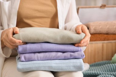 Bir yığın şık elbisesi olan genç bir kadın evde, yatağında oturuyor.