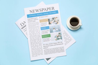 Gazeteler ve bir fincan kahve mavi arka planda. Üst görünüm