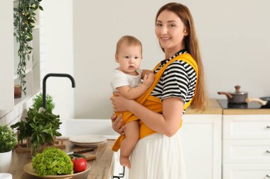 Mutfakta küçük bir bebeği olan mutlu genç bir anne.