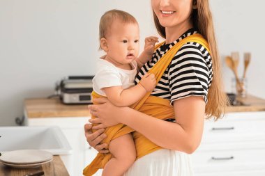 Mutfakta küçük bir bebeği olan mutlu genç bir anne.