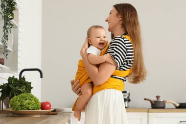 Mutfakta küçük bir bebeği olan mutlu genç bir anne.