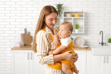 Mutfakta küçük bir bebeği olan genç bir anne.