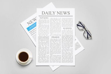 Gri arka planda bardak ve bir fincan kahve olan farklı gazeteler.