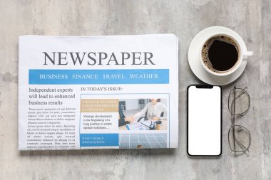 Gözlüklü gazete, cep telefonu ve grunge fonda bir fincan kahve.