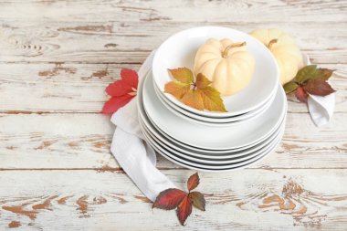 Ahşap zemin üzerinde sonbahar dekoru ve balkabağı olan tabak yığını