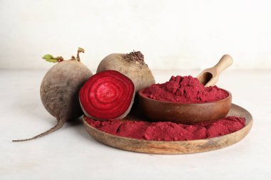 Canlı pancar tozu dolu ahşap bir tabak kepçe, kase ve beyaz arka planda taze pancar.