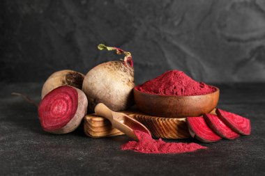 Ahşap bir kase canlı pancar tozu kepçeli ve siyah arka planda taze pancarlar.