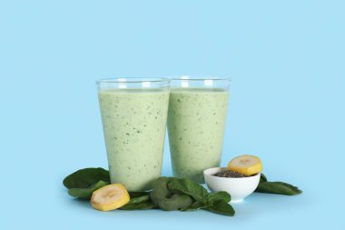 Muzlu taze ıspanaklı smoothie ve mavi arka planda bir kase chia tohumu.