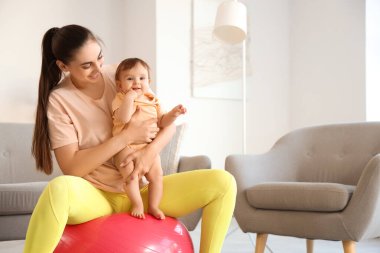 Küçük bebeğiyle evde fitbol oynayan sporcu bir anne.