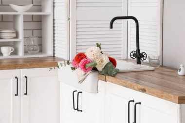 Mutfak tezgahındaki lavaboda bir buket güzel yıldız çiçeği.