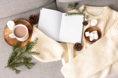 Kakaolu boş kitap, lokum ve kanepede sıcak süveter, üst manzara.