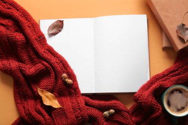Boş açık kitaplı kompozisyon, sıcak örgü eşarp ve arka planda bir fincan kahve.