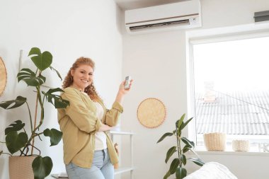 Evinde klimalı, gülümseyen genç bir kadın.