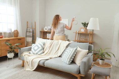 Evinde klima uzaktan kumandalı güzel, mutlu genç bir kadın. Arka plan